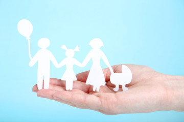 Family figures in female hand on blue background