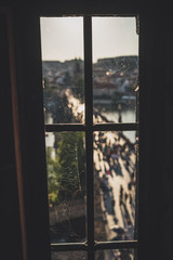 Fototapeta premium Old dirty window with spider web on Old Town Bridge Tower with blurred Charles Bridge in background. Prague, Czech Republic.