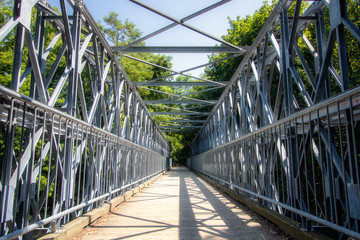 Long pedestrian bridge cutting through a lush green wooded park area. Chedoke Radial Trail, Hamilton Ontario. 