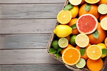 Citrus fruits with green leafs in basket on wooden table