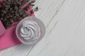Lavender marshmallows in a paper basket. Near a bouquet of lavender wrapped in paper.