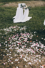 stylish floral decor of wedding aisle, rose petals on grass and modern wooden box for gifts from...