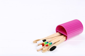 Bamboo toothbrushes in basket on white wooden table