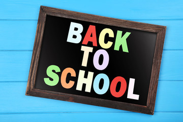 Text Back To School with black frame on blue wooden table