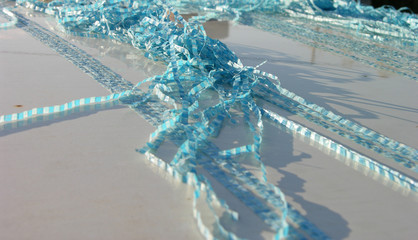 fragments of old blue polyethylene tarpaulin lie randomly on the metal surface.  the wind and the...