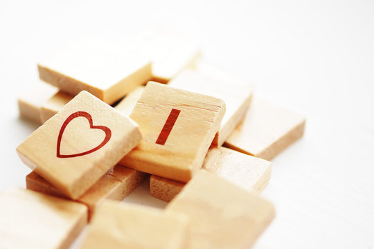 Word I LOVE and heart symbol pictured on wooden cubes on white background, soft focus