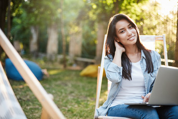 Urban youth lifestyle, students and e-learning concept. Charming smiling brunette woman touching...