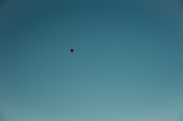 Naklejka na ściany i meble Tiny hot air ballon on the blue sky in fresh winter morning background.