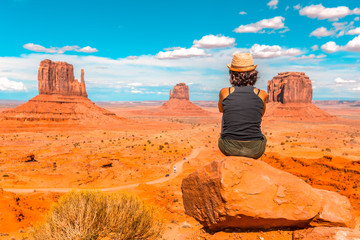 A young girl with black t-shirt sitting to the right of the photo on a stone in the Monument Valley National Park in the visitor center. Utah
