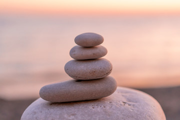 Fototapeta na wymiar Perfect balance of stack of pebbles at seaside towards sunset. Concept of balance, harmony and meditation. Helping or supporting someone for growing or going higher up.