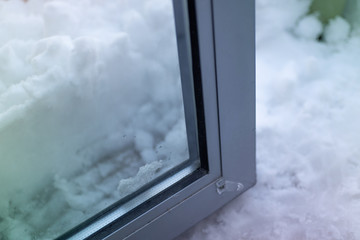 The glass door stuck (does not opening) next to snowdrift after winter storm. Toned effect.