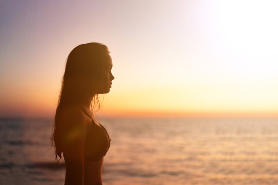 Silhouette of beautiful young gracile pensive woman with a freedom feeling at a beautiful sunset. Freedom and travel adventure happy feeling concept.