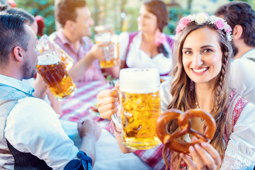 Woman toasting to the camera with glass of beer in Bavarian pub