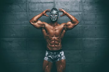 Tableaux ronds sur aluminium Carnaval Homme musclé mystérieux se cachant derrière le masque Flexing Muscles. Bodybuilder avec masque sur son visage posant.