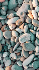  Pebble texture with a Abstract background of large pebbles lit by the sun. Pebble texture with a blue tint. Stone background. Pebble beach with multi-colored stones. Turquoise. Vertical framblue tint