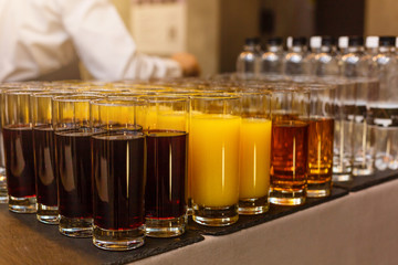 Rows of glasses with non alcoholic drinks, orange juice and water. Drinks on a buffet table. Catering