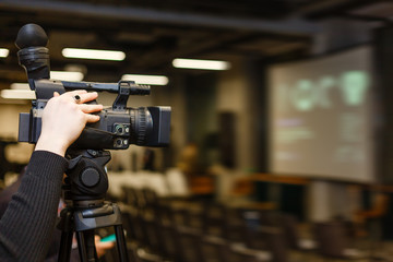 Camera man recording event with professional video camera Panasonic. Blurred background