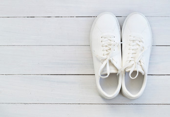 Fashion blog or magazine concept. White female sneakers on wooden background. Flat lay, top view minimal background.