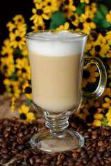 Latte coffee. Coffee with milk. Cappuccino in a glass cup on a wooden table. Cappuccino coffee and roasted coffee beans.