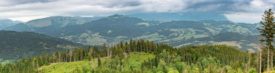 Scenic panorama view of the mountain landscape, forests, pastures, meadows and small villages with a cloudy sky covering the Alps.Department of Haute-Savoie, region of Auvergne-Rhone-Alpes in France.