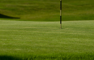 Obraz premium Green of a golf course, with the flagpole in the hole, grass, sunset, lesson, sport, concentration, hobby, mountain, vacation, Trentino, Alto Adige, Italy