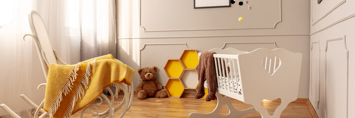 Panoramic view of cute yellow and grey baby bedroom with rocking chair with blanket and white...
