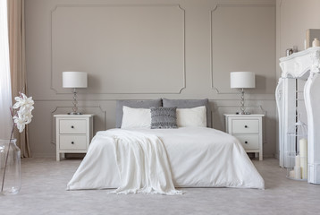 New york style bedroom interior with symmetric design, copy space on empty grey wall