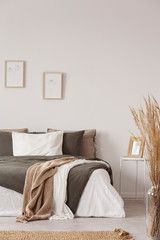 Graphics in wooden frames on white empty copy space wall in bedroom with comfortable bed with black...