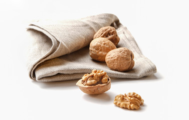 group of cracked walnuts on a kitchen cloth on a white backdrop