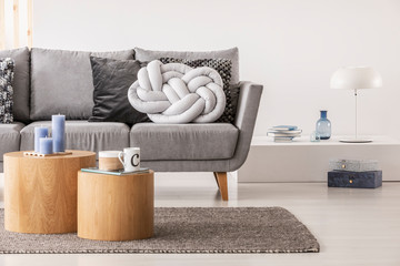 Trendy knot light grey pillow on comfortable scandinavian couch