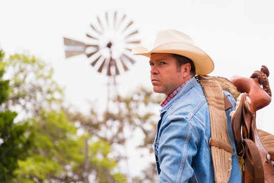 Texas, Cowboy with saddle and ranch windmill in background