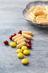 Coenzyme Q10 capsules, Vitamin C and Beta-Carotene tablets. Antioxidants. Concept for a healthy dietary supplementation. Bright wooden background. Close up. Copy space.  