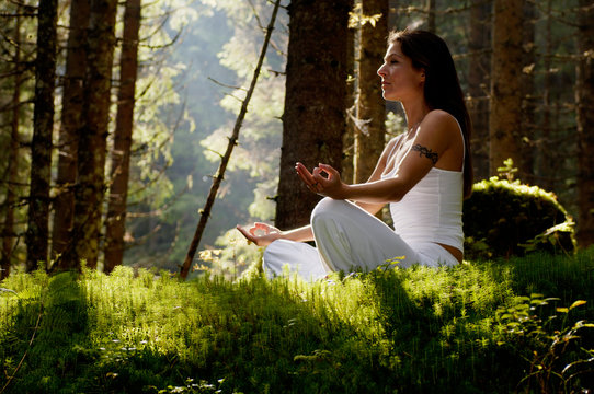 Young woman mediating in forest