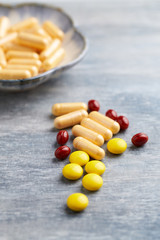 Vitamin C, Beta-Carotene tablets and Coenzyme Q10 capsules. Antioxidants. Concept for a healthy dietary supplementation. Bright wooden background. Close up. Copy space.  