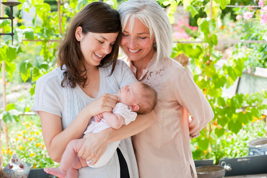 Germany, Bavaria, Grandmother and mother adoring baby in garden