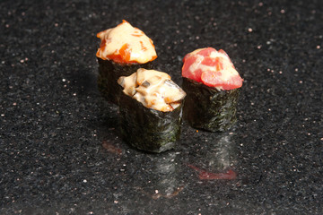 Sushi rolls on black marble background. Fresh Hosomak, Maki, Nigiri, Tempura, Uramaki, Philadelphia pieces with rice, nori and fish. Japanese cusine, Asian food.