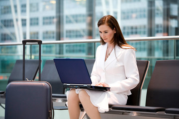 Business woman sitting in airport lounge, using laptop