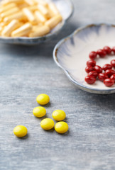 Vitamin C, Beta-Carotene tablets and Coenzyme Q10 capsules. Antioxidants. Concept for a healthy dietary supplementation. Bright wooden background. Close up. Copy space.  
