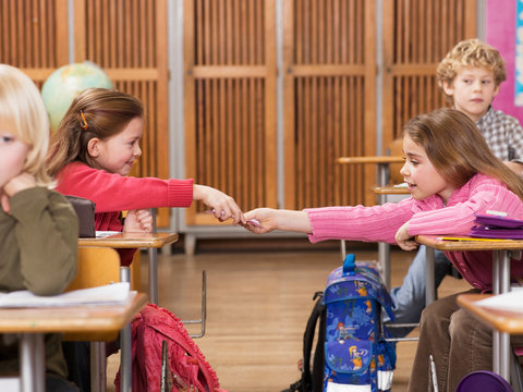 Girls exchanging notes in classroom