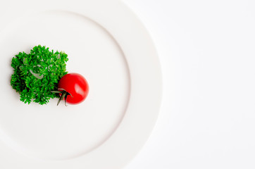 Close up top view of green parsley and red tomato on white dish with copy space on white background, Diet food, vegan and  vegetarian food concept.