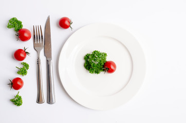 Close up top view of green parsley and red tomato on white dish with copy space on white background, Diet food, vegan and vegetarian food concept.