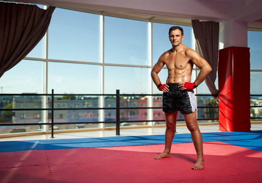 Fighter with hands wrapped standing by the window in the gym at sunset