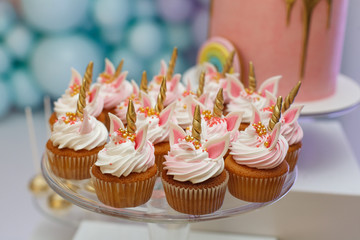 birthday party of a baby concept unicorn. girls birthday decorations. A beautiful bright cupcakes on a stand decorated in the form of fantasy unicorn.The concept of  festive dessert for girls birthday