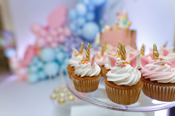 birthday party of a baby concept unicorn. girls birthday decorations. A beautiful bright cupcakes on a stand decorated in the form of fantasy unicorn.The concept of  festive dessert for girls birthday