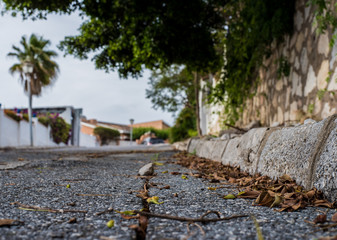 Fototapeta na wymiar abandoned and broken road in mijas, with leafy trees and houses at the end
