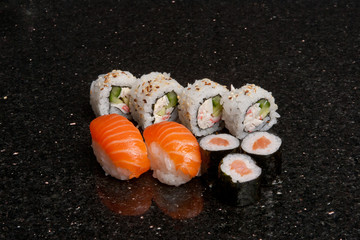 Sushi rolls on black marble background. Fresh Hosomak, Maki, Nigiri, Tempura, Uramaki, Philadelphia pieces with rice, nori and fish. Japanese cusine, Asian food.