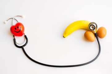 banana and two eggs representing men's penis with stethoscope and smile red heart on white...