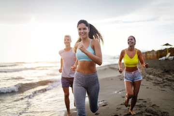 Group of friends running at the beach on beautiful summer sunset