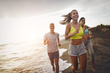 Group of sport people running on the beach