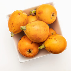 Fresh loquats (medlars) in bowl. Isolated on white background. Close-up.Top view.